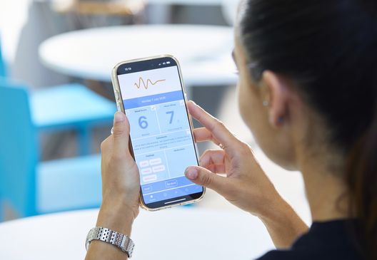 image of woman's side profile holding up her mobile phone using the mood tracker app